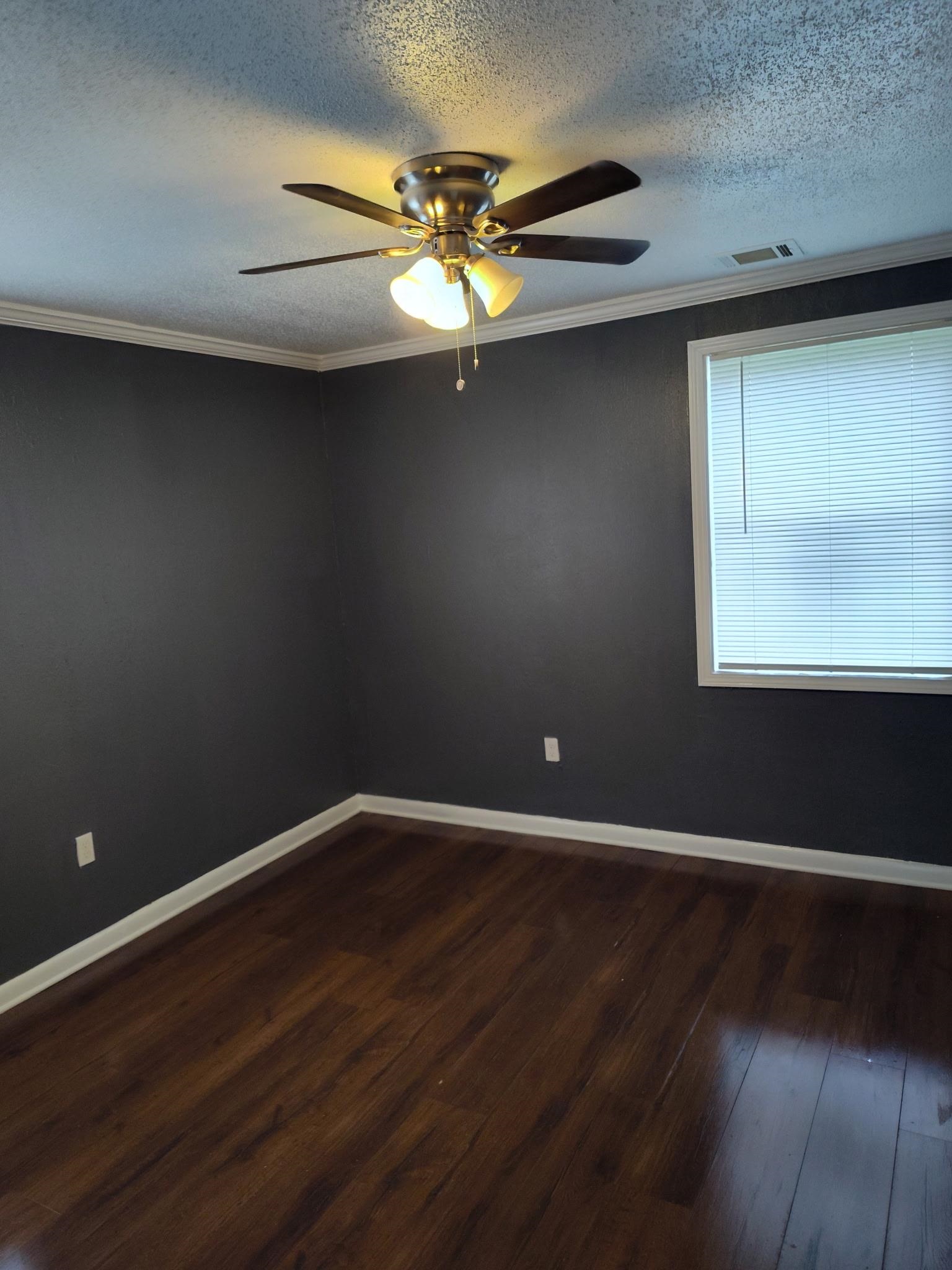 258 Silverage Avenue Memphis, TN 38109 - Photo 7 of 8 Empty room with ornamental molding, dark wood finished floors, a textured ceiling, and ceiling fan