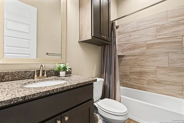 a bathroom with a granite countertop bathtub sink vanity mirror and toilet