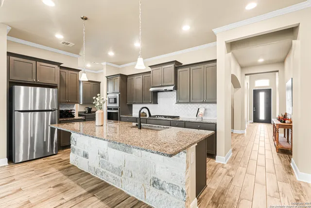 a large kitchen with kitchen island a large counter top space a sink stainless steel appliances and cabinets