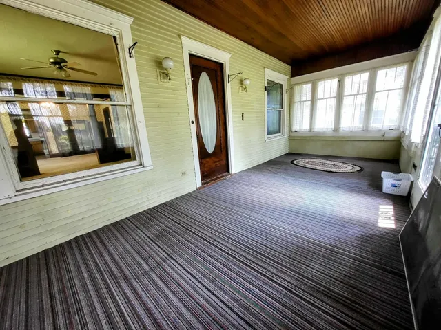 a view of an empty room with wooden floor and windows