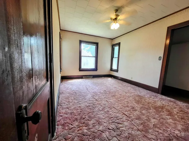 an empty room with windows and fan