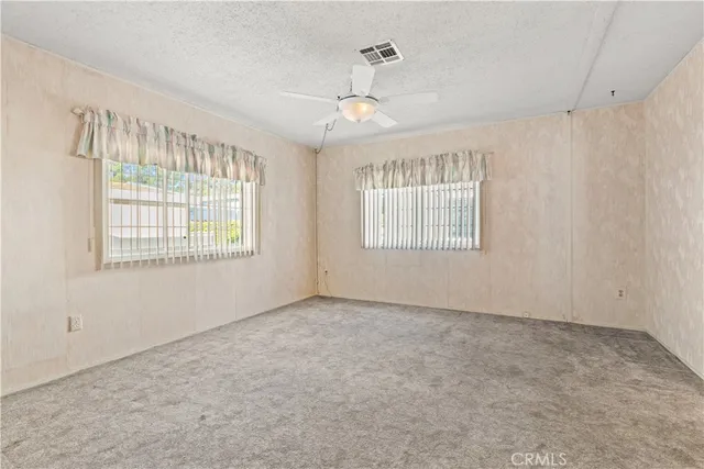 an empty room with fan and windows