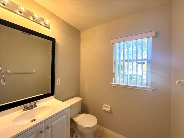 a bathroom with a granite countertop sink toilet and mirror