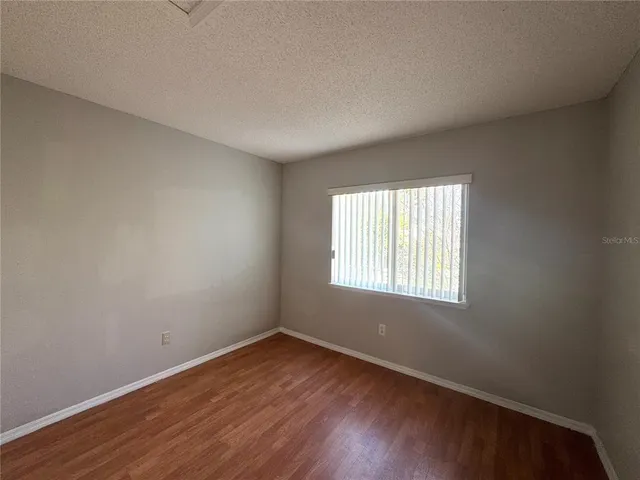 an empty room with wooden floor and window