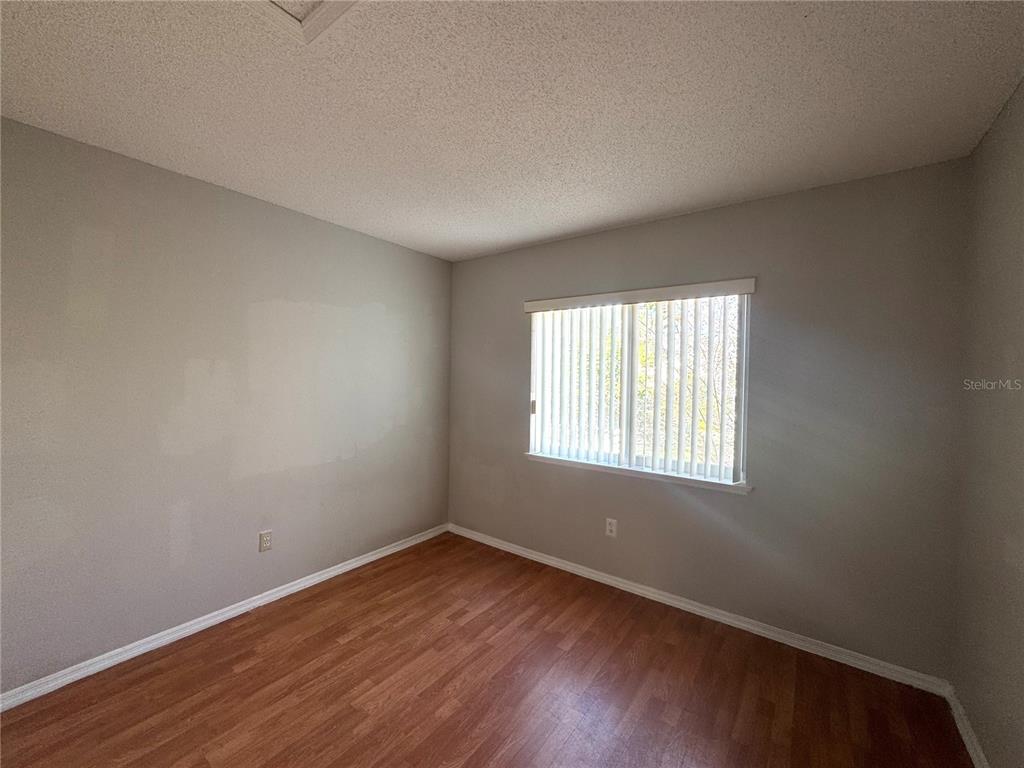 14328 Rainsong Drive Orlando, FL 32824 - Photo 15 of 27 an empty room with wooden floor and window