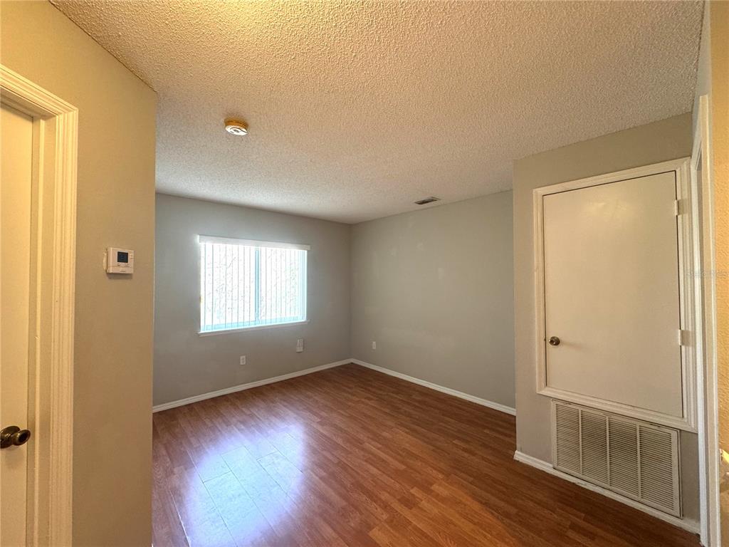 14328 Rainsong Drive Orlando, FL 32824 - Photo 19 of 27 an empty room with wooden floor and windows