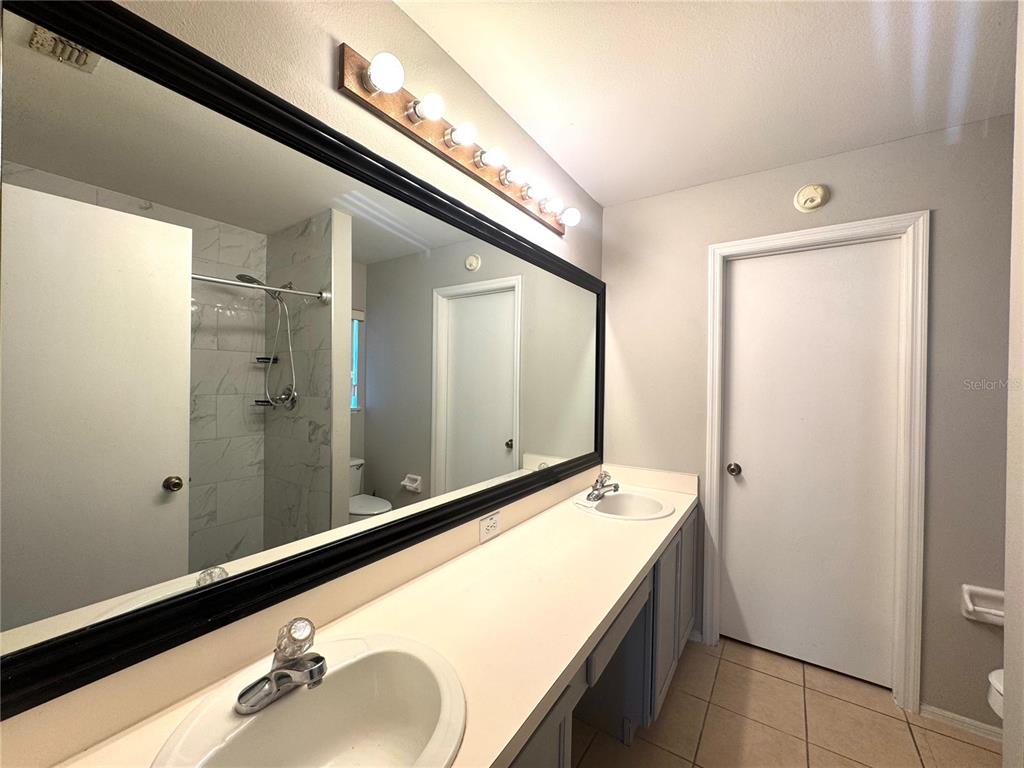 14328 Rainsong Drive Orlando, FL 32824 - Photo 23 of 27 a bathroom with a granite countertop sink and a mirror