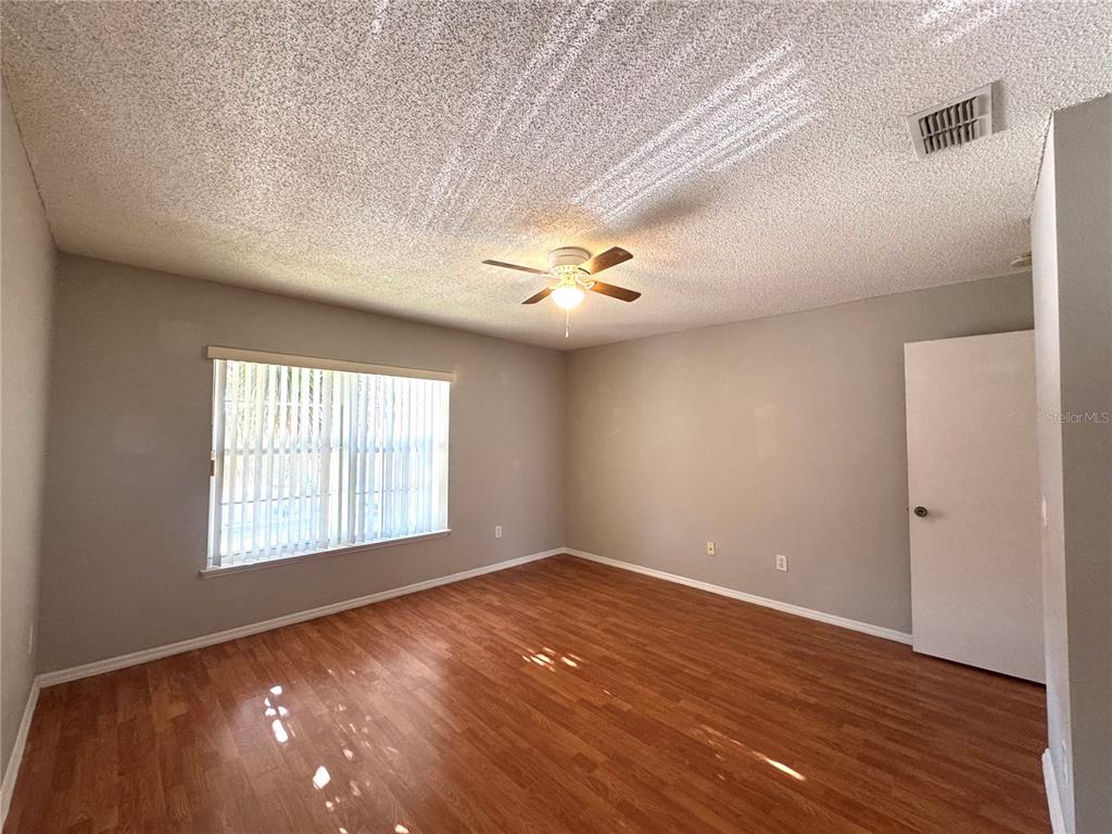 14328 Rainsong Drive Orlando, FL 32824 - Photo 24 of 27 an empty room with wooden floor and windows
