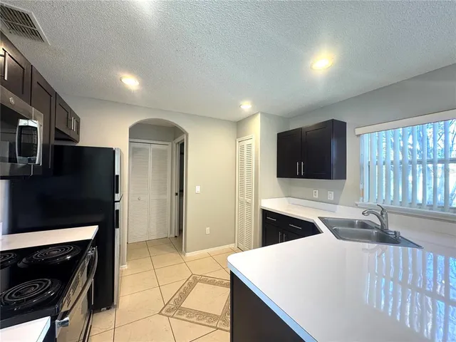 a living room with stainless steel appliances furniture a fireplace and a flat screen tv