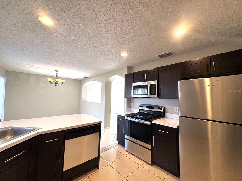 14328 Rainsong Drive Orlando, FL 32824 - Photo 10 of 27 a kitchen with granite countertop a refrigerator stove and sink