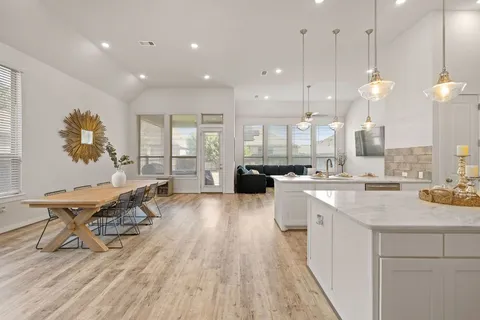 a large kitchen with lots of counter space a sink appliances and living room view