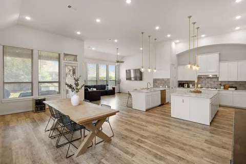 a kitchen with a table chairs wooden floors and white cabinets