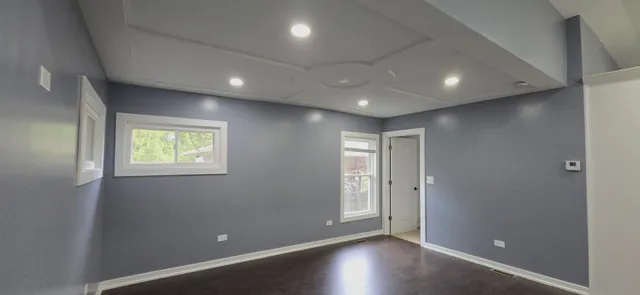 an empty room with wooden floor and windows with curtains
