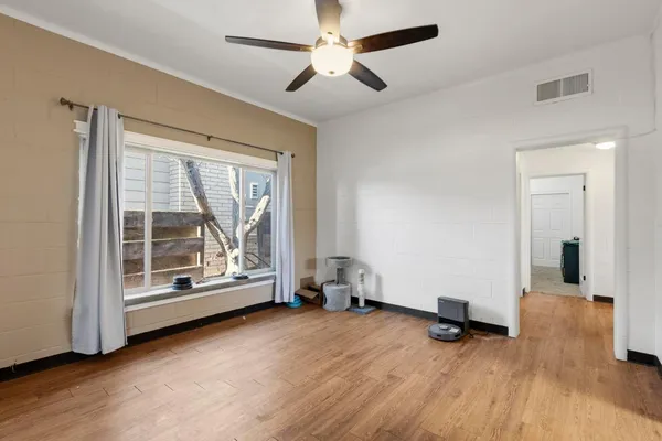 a view of empty room with wooden floor and fan