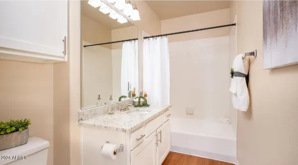 a bathroom with a granite countertop sink a mirror and a bathtub
