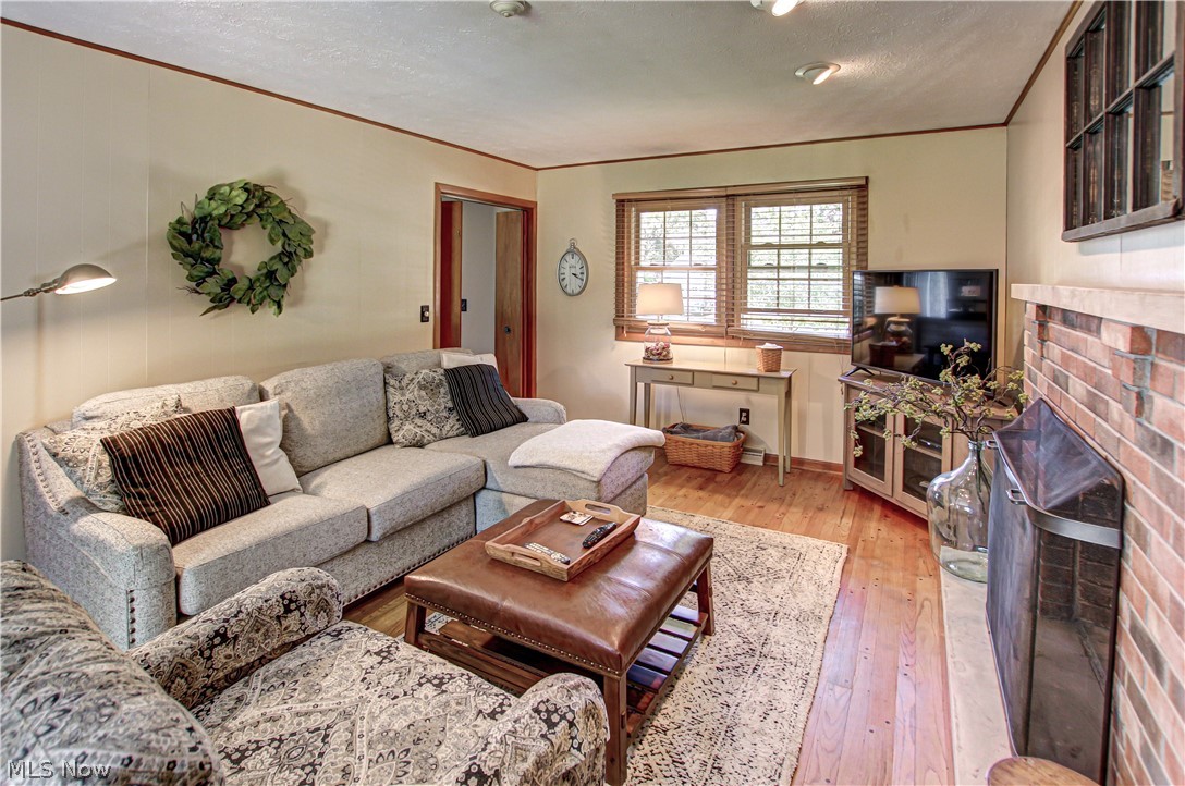 910 Andrews Road Medina, OH 44256 - Photo 17 of 45 Family room with a textured ceiling, light hardwood / wood-style flooring, a fireplace, and crown molding
