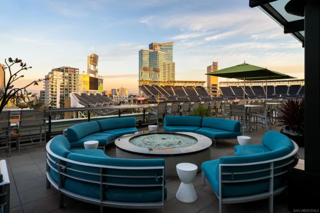 a row of palm trees sitting in patio with a swimming pool and furniture