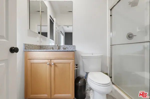 a bathroom with a granite countertop sink a toilet and shower