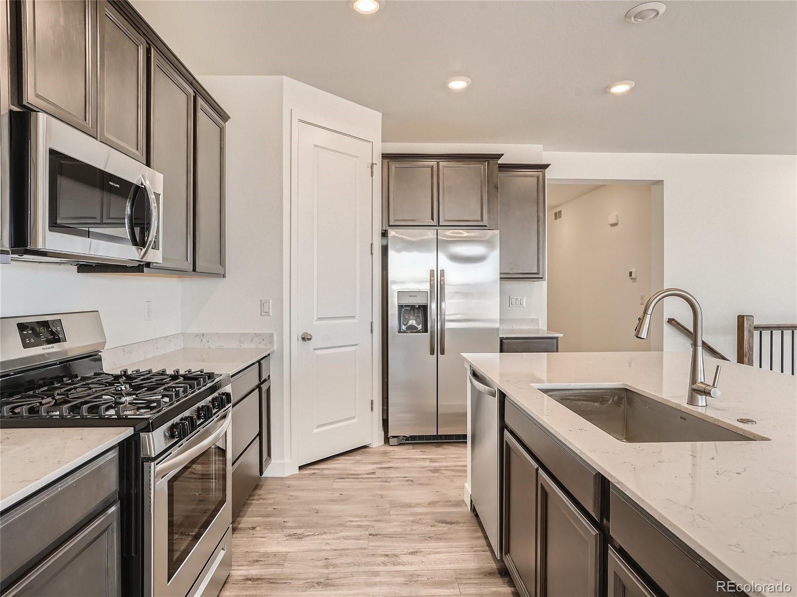 9975 Uvalda Street Commerce City, CO 80022 - Photo 11 of 29 a kitchen with stainless steel appliances granite countertop a sink stove and refrigerator