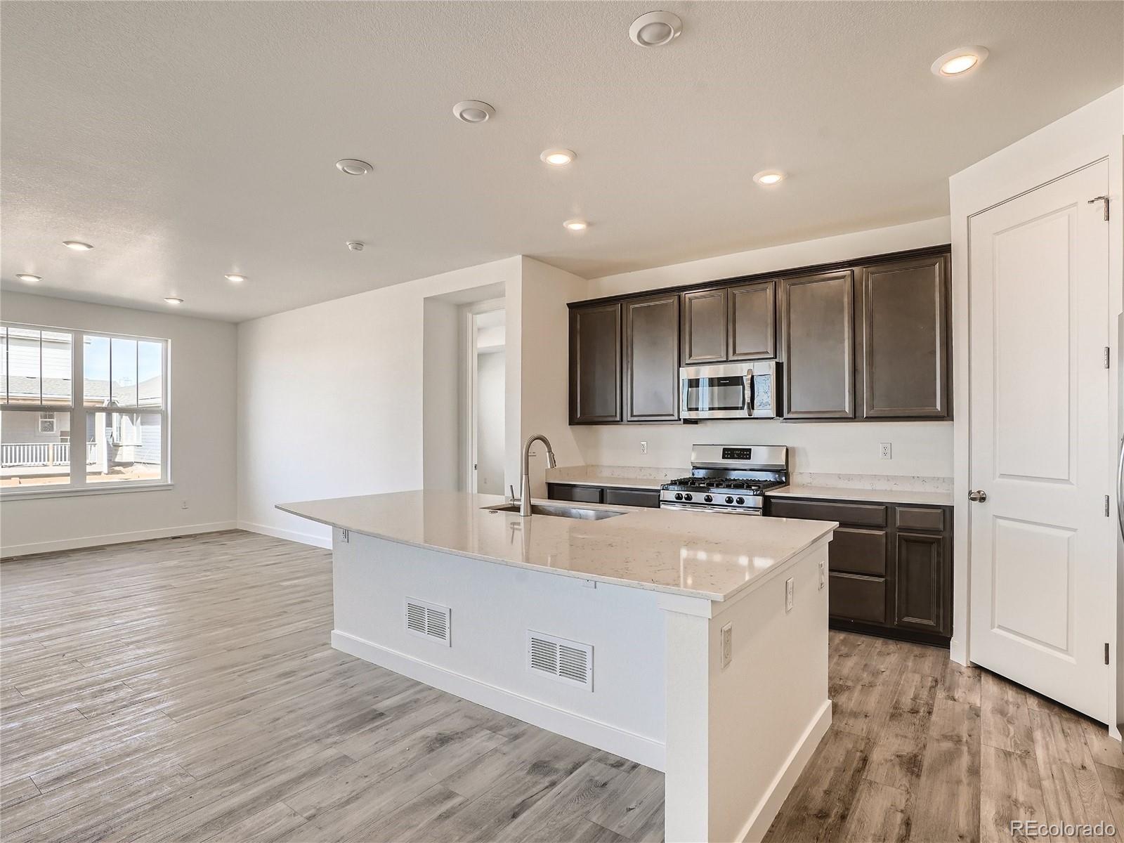 9975 Uvalda Street Commerce City, CO 80022 - Photo 13 of 29 a kitchen with stainless steel appliances granite countertop a stove top oven a sink and a refrigerator
