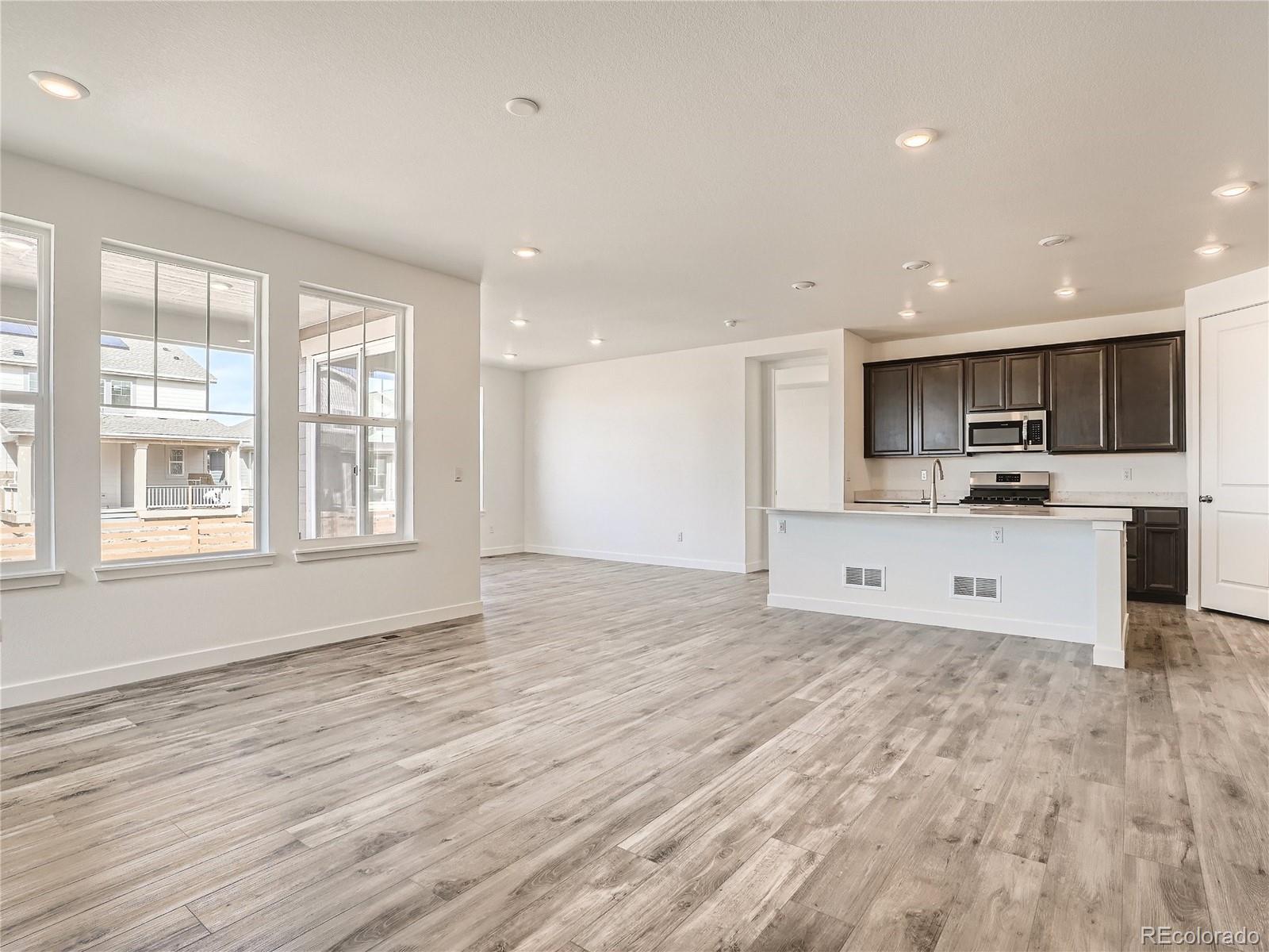 9975 Uvalda Street Commerce City, CO 80022 - Photo 7 of 29 a large kitchen with stainless steel appliances kitchen island a large counter top and a wooden floors