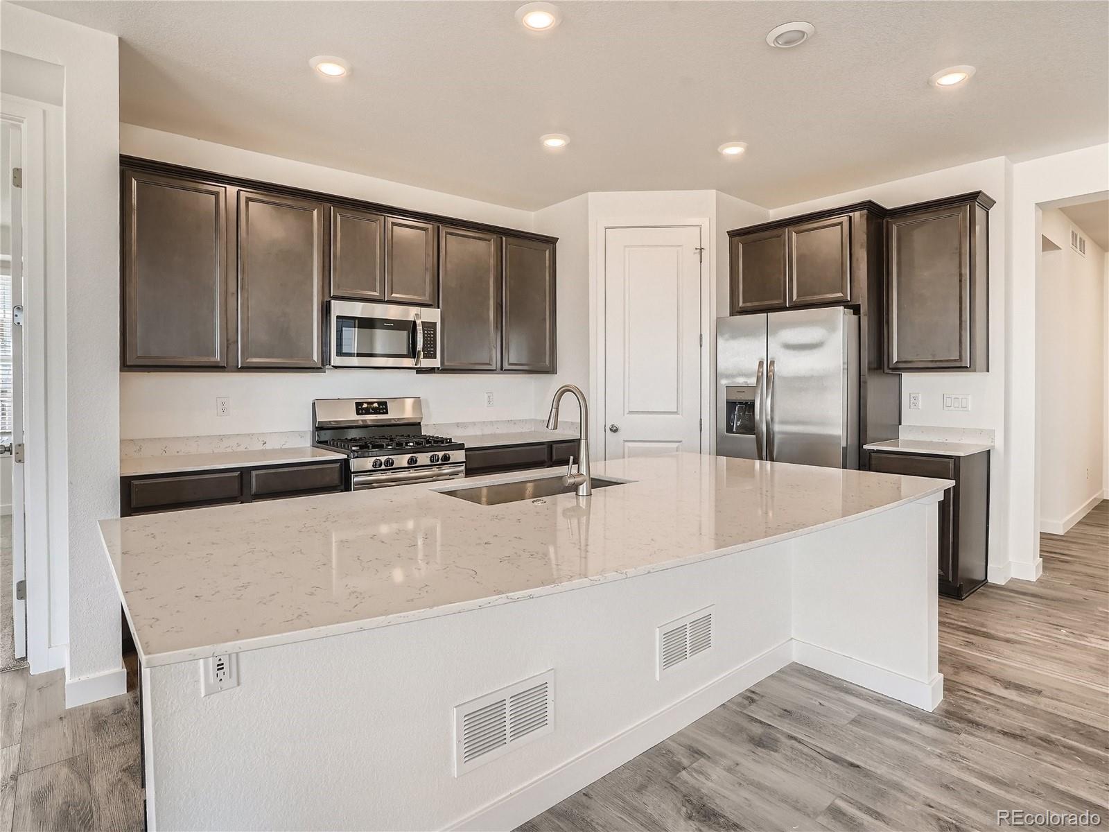 9975 Uvalda Street Commerce City, CO 80022 - Photo 10 of 29 a large kitchen with stainless steel appliances and a refrigerator