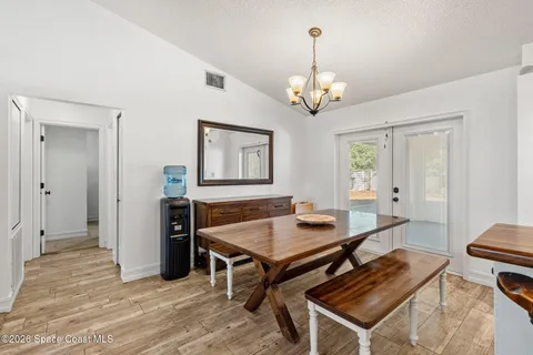 a living room with dining table and a chandelier