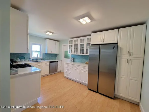 a kitchen with stainless steel appliances granite countertop a refrigerator a sink and white cabinets
