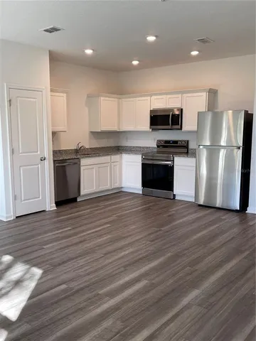 a kitchen with stainless steel appliances wooden floors and white cabinets