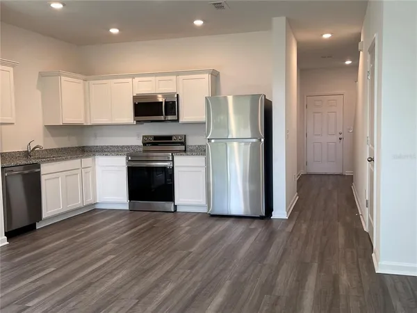 a kitchen with wooden floors and stainless steel appliances