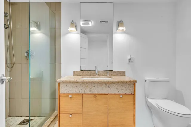 a bathroom with a granite countertop sink a toilet and a mirror