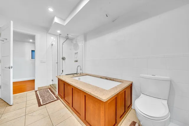 a spacious bathroom with a granite countertop sink a toilet a mirror and bathtub