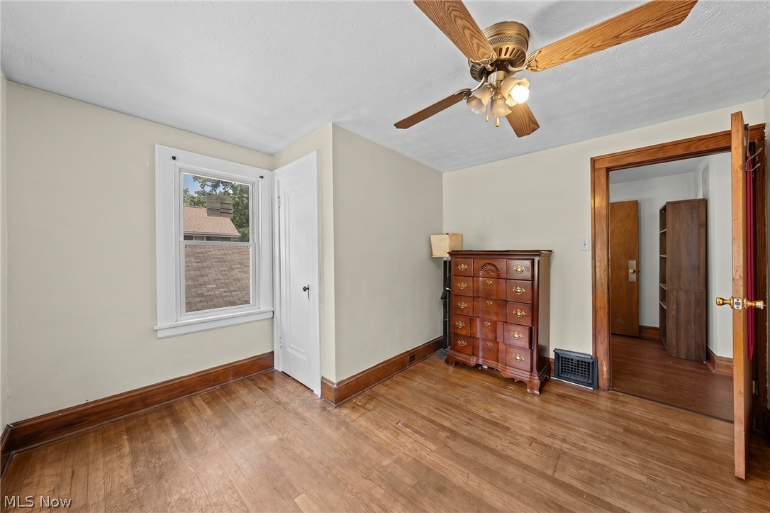 819 Keeney Street Akron, OH 44310 - Photo 12 of 24 Room featuring wood-finish flooring, a ceiling fan with light fixture, and a window with white trim