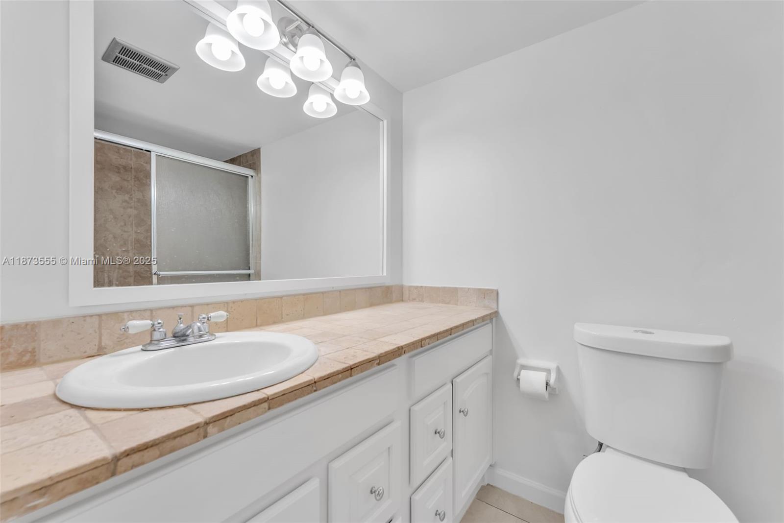 3100 North Pine Island Road, Unit 304 Sunrise, FL 33351 - Photo 13 of 24 a bathroom with a granite countertop toilet sink and mirror
