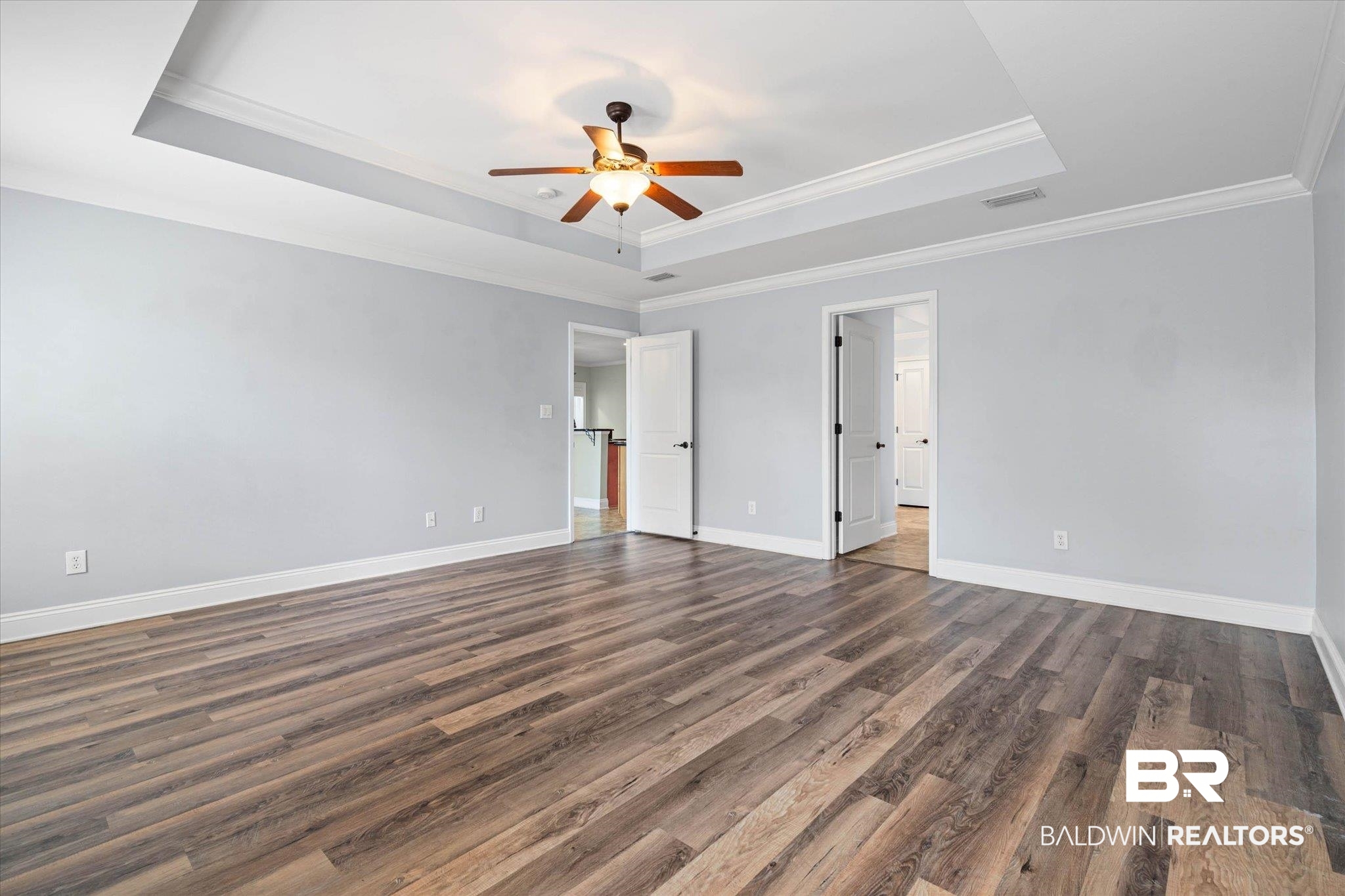 704 Edinburgh Avenue Foley, AL 36535 - Photo 18 of 32 Primary bedroom featuring dark wood finished floors, a ceiling fan, a raised ceiling, and crown molding