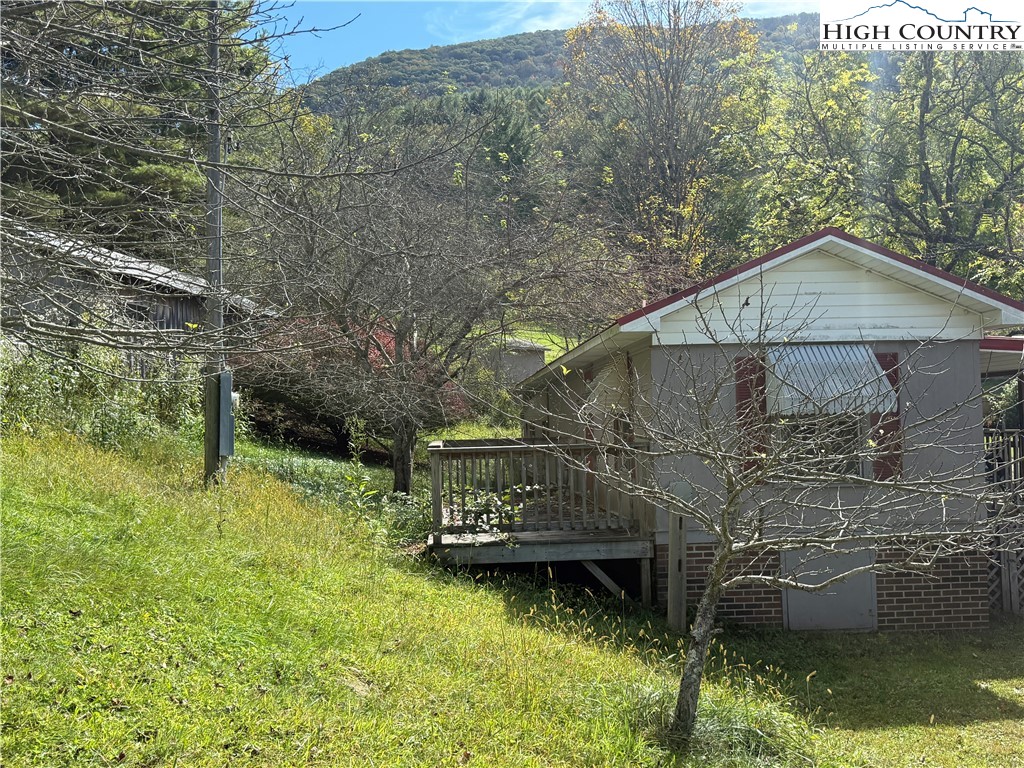 253 Bobby Rash Road Warrensville, NC 28693 - Photo 13 of 15 a backyard of a house with large trees and brick walls