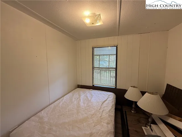 a bedroom with a bed next to a window with wooden floor
