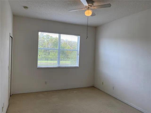 an empty room with a window and a fan
