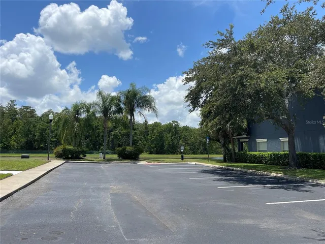 a view of a brick house next to a yard and large trees