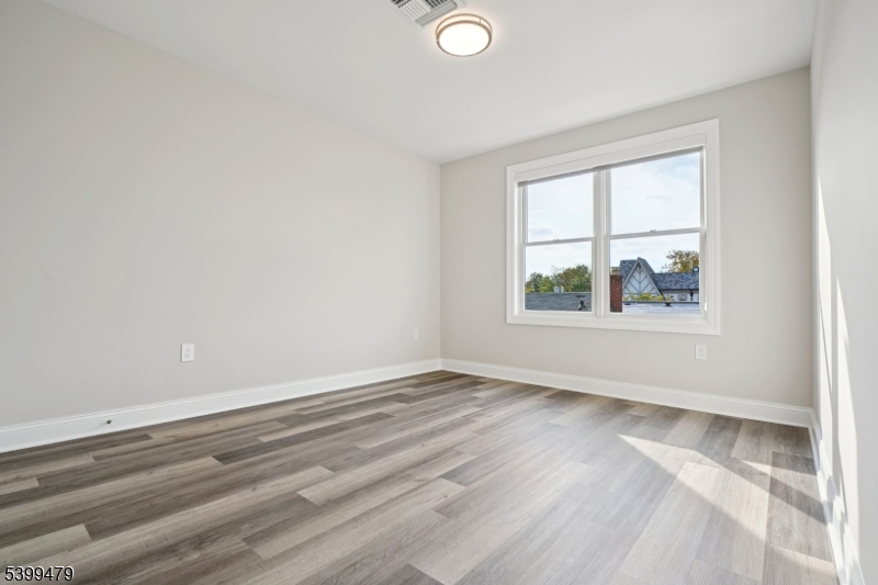 246 Main Street, Unit 202 Chatham, NJ 07928 - Photo 11 of 29 an empty room with wooden floor and windows