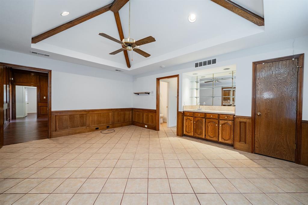 8304 Navigation Drive Rowlett, TX 75088 - Photo 17 of 40 Unfurnished room with wainscoting, a tray ceiling, a ceiling fan, light tile patterned flooring, and beamed ceiling