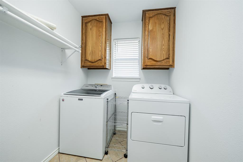 8304 Navigation Drive Rowlett, TX 75088 - Photo 20 of 40 Laundry area featuring washer and clothes dryer, cabinet space, and light tile patterned flooring