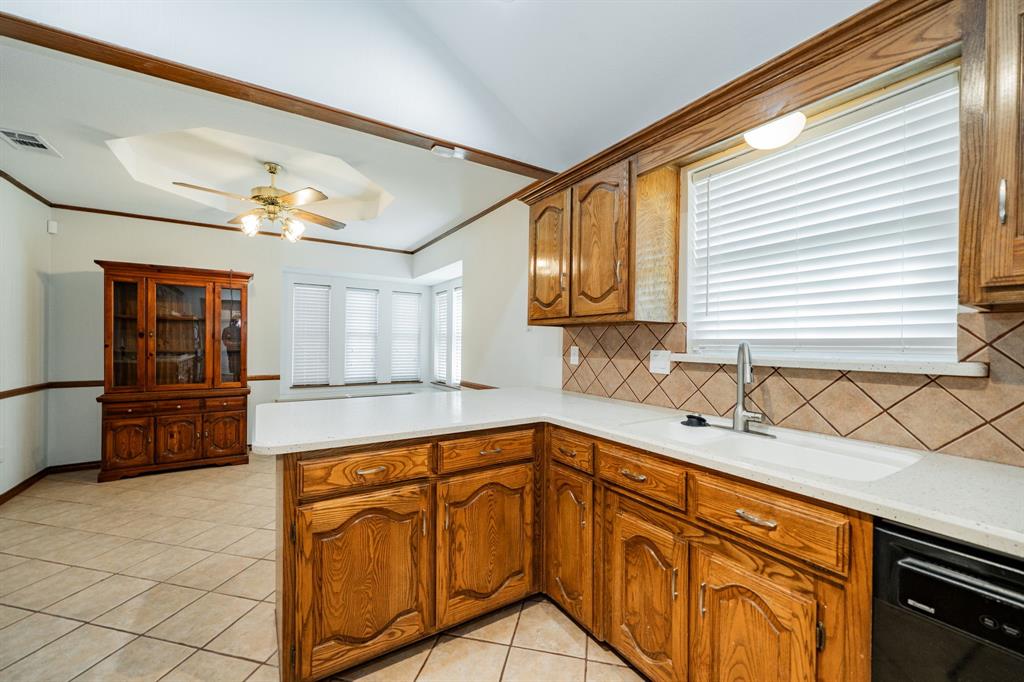 8304 Navigation Drive Rowlett, TX 75088 - Photo 7 of 40 Kitchen featuring dishwasher, decorative backsplash, light tile patterned floors, a peninsula, and brown cabinets