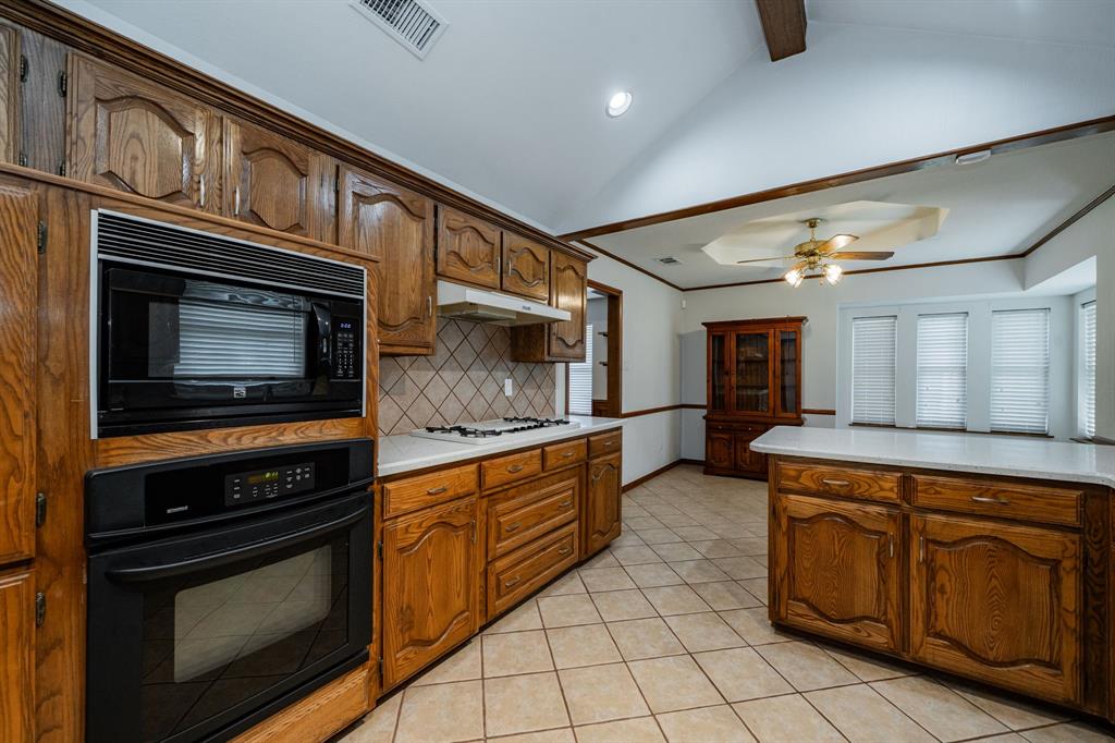 8304 Navigation Drive Rowlett, TX 75088 - Photo 8 of 40 Kitchen with black appliances, light tile patterned floors, decorative backsplash, brown cabinets, and crown molding