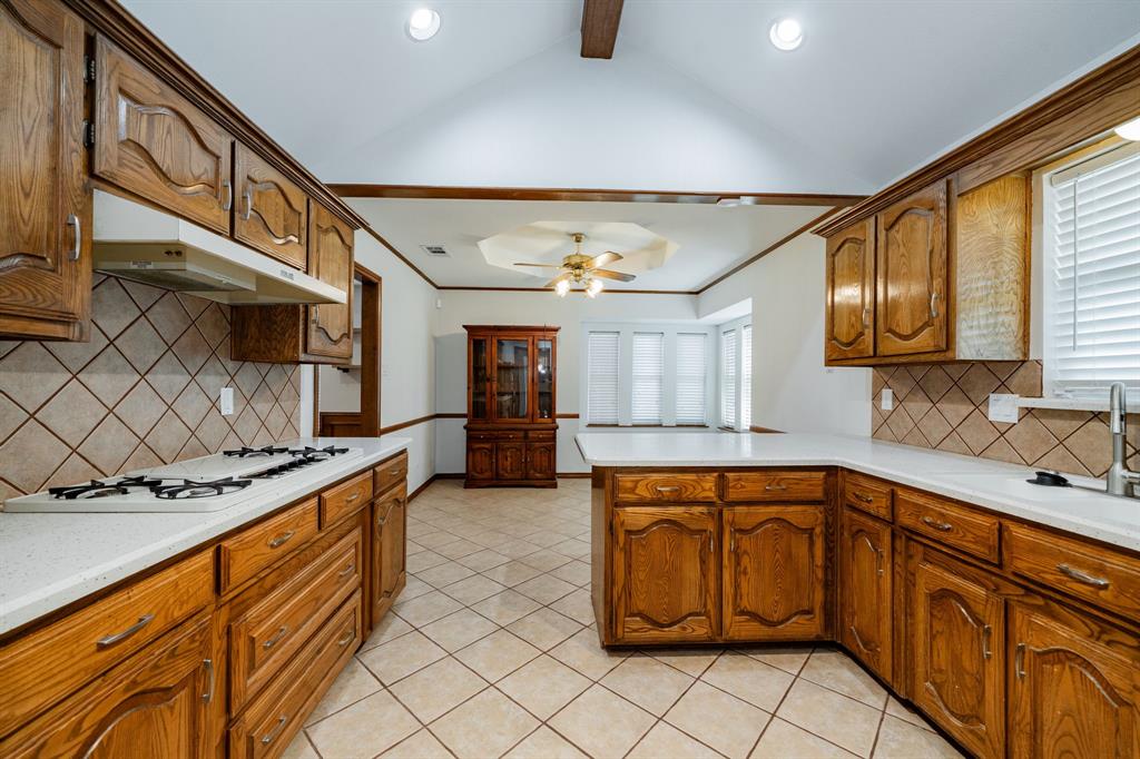 8304 Navigation Drive Rowlett, TX 75088 - Photo 9 of 40 Kitchen with tasteful backsplash, brown cabinets, a peninsula, light tile patterned flooring, and a ceiling fan