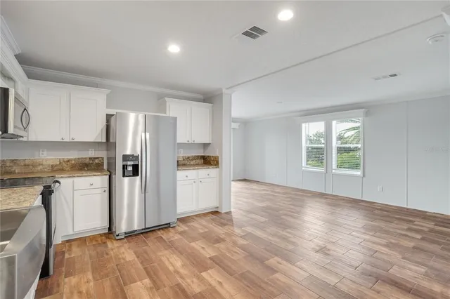 a view of kitchen with refrigerator cabinets and wooden floor