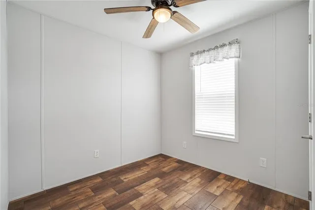 an empty room with a window and a fan