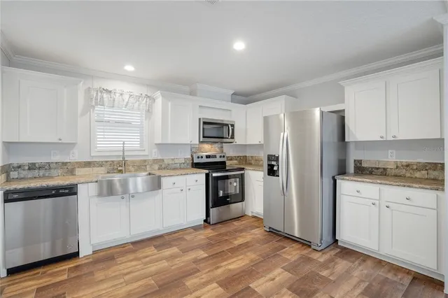 a kitchen with granite countertop white cabinets and stainless steel appliances
