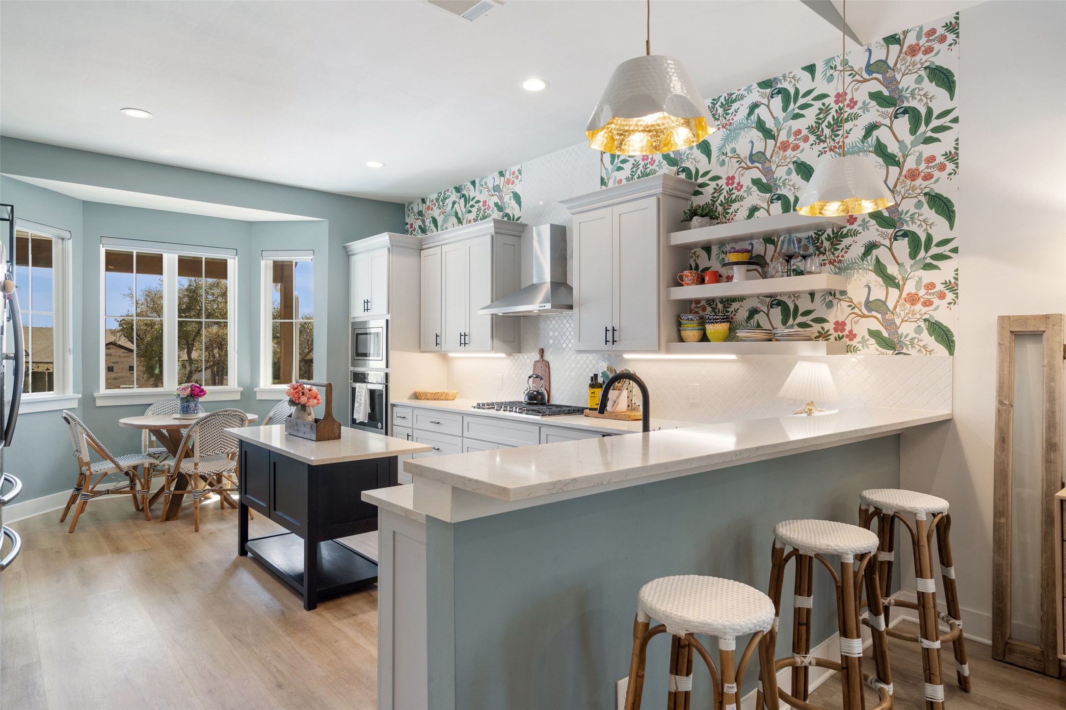 170 Bunker Rnch Boulevard, Unit 28 Dripping Springs, TX 78620 - Photo 4 of 37 Kitchen with a kitchen bar, open shelves, light stone counters, light wood-style flooring, and a peninsula
