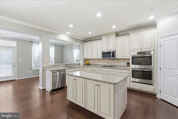 a kitchen with stainless steel appliances granite countertop a stove top oven a sink and a refrigerator